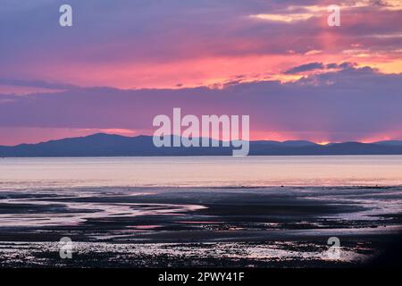 Le colline di Dumfries e Galloway al tramonto, visto attraverso il Solway Firth da Allonby, Cumbria Foto Stock