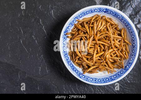 Farina di verme con peperoncino. Vermi salati fritti. Worm al forno. Alimentazione sana. Foto Stock