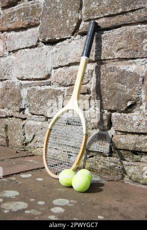 Tre palle da tennis e racchetta vintage sul sentiero Foto Stock