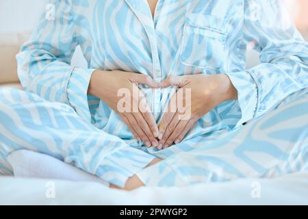 Gravidanza, donna e mani di cuore sullo stomaco incinta di una futura madre pronta per il bambino con amore. Benessere, speranza e segno di mano per mostrare gratitudine, fait Foto Stock