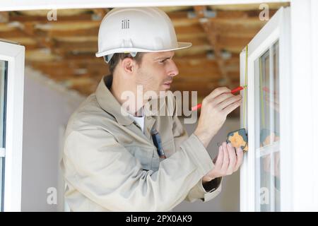 architetto che prende misure di una finestra in un nuovo appartamento Foto Stock