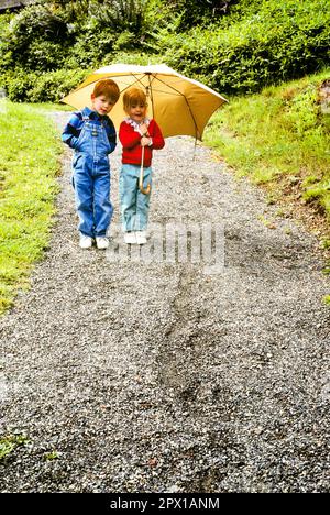 1980S RAGAZZO E RAGAZZA FRATELLO E SORELLA IN PIEDI INSIEME SU SENTIERO DI GHIAIA SOTTO OMBRELLO GIALLO - KJ11476 LGA001 HARS WINNING BROTHERS RURAL HEALTHINESS HOME VITA COPIA SPAZIO FULL-LENGTH MASCHI PREMUROSI FRATELLI SORELLE OCCHIO CONTATTO PERCORSO FELICITÀ BENESSERE E PROGRESSO RICREAZIONE REDHEAD SU SORELLA MINORE ROSSO CAPELLI CONCETTUALE PIACEVOLE PIACEVOLE PIACEVOLE AFFASCINANTE GHIAIA CRESCITA GIOVANILE AMABILE PIACEVOLE RELAX INSIEME ADORABILE ATTRAENTE GRANDE FRATELLO CAUCASICO ETNIA VECCHIO STILE Foto Stock