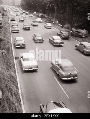 1950S TRAFFICO ESTIVO SU EXPRESSWAY DIVERSE AUTO TIRATE SOPRA CON MOTORI SURRISCALDATI - M5077 HAR001 HARS COOPERAZIONE MOTORI STAGIONE PARKWAY DIVERSE VACANZE NERO E BIANCO EXPRESSWAY HAR001 VECCHIO STILE SURRISCALDATO Foto Stock