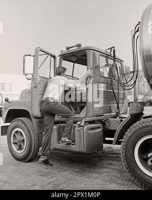 1970S VISTA POSTERIORE DEL CONDUCENTE DEL VEICOLO SALIRE IN CABINA DEL SUO VEICOLO PER IL TRASPORTO DI PRODOTTI CHIMICI ALLA RINFUSA - M9608 HAR001 HARS SKILLS ADVENTURE CHEMICAL IL SUO SERVIZIO CLIENTI TRUCKER BASSO ANGOLO DI LAVORO POSTERIORE GUARDARE IN ALTO OCCUPAZIONE DA DIETRO VEICOLI GRANDI RIG DIPENDENTE HAUL INDIETRO VISTA UOMO MEDIO-ADULTO DONNA METÀ-ADULTO AUTOTRASPORTI GIOVANE UOMO ADULTO NERO E BIANCO ETNICITÀ CAUCASICA HAR001 LAVORARE IN VECCHIO STILE Foto Stock