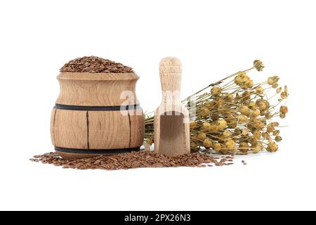 Semi di lino in barile di legno vicino a mazzo di piante di lino e paletta di legno isolata su fondo bianco Foto Stock