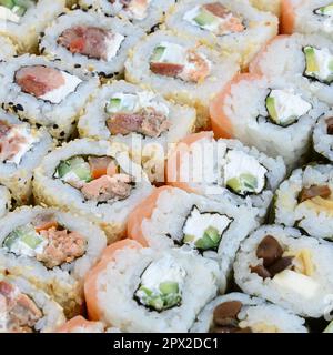 Primo piano di un sacco di sushi roll con diversi ripieni. Macrofo di cucina classica giapponese cotta. Immagine di sfondo Foto Stock