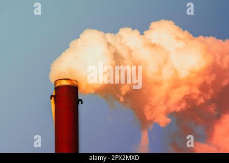 Fumo arancione denso e pesante che esce da un camino di fabbrica chimica sotto uno sfondo cielo. Foto Stock