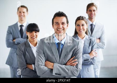Entusiasta e fiduciosa. Ritratto di un manager aziendale sicuro che attraversa le braccia e si trova in piedi con il suo team. Foto Stock