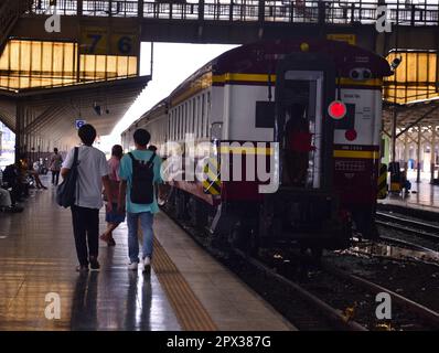 Le persone camminano verso un treno in attesa su un binario alla stazione ferroviaria di Hua Lampong, Bangkok, Thailandia. Anche se molti dei treni si sono spostati in una nuova stazione ferroviaria nel nord della città, alcuni treni partono ancora dalla stazione ferroviaria di Hua Lampong, Foto Stock