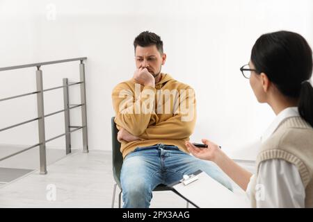 Psicoterapeuta che lavora con l'uomo tossicodipendente al chiuso Foto Stock