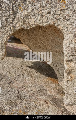 Primo piano di roccia ruvida con profonde crepe, buchi e fessure da vento, calore o erosione di acqua da riscaldamento globale o cambiamento climatico. Dettagli texture e. Foto Stock