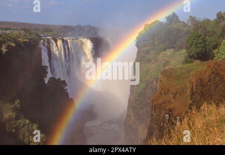 Un arcobaleno sulle Cascate Vittoria, con entrambe le sponde dello Zimbabwe e dello Zambian in vista. Foto Stock