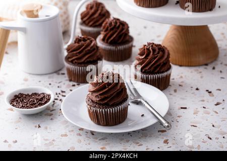 Cupcake al cioccolato con glassa di ganache montata al cioccolato fondente e spruzzate di cioccolato Foto Stock