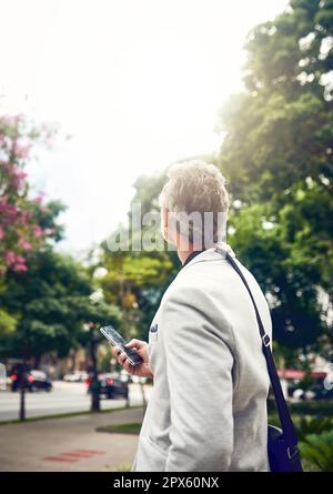 Grande città, grandi ambizioni. un uomo d'affari maturo che usa un cellulare in città Foto Stock