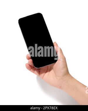 La mano di una donna tiene in mano uno smartphone con uno schermo nero vuoto su uno sfondo bianco isolato Foto Stock