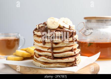 Gustose frittelle con banana a fette servite su un tavolo bianco Foto Stock