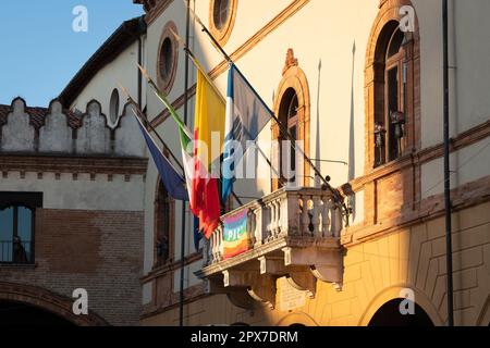 Vista laterale della facciata principale del municipio di Ravenna dal balcone sono esposte 4 bandiere, europee, italiane, regionali e una bandiera della città. Foto Stock