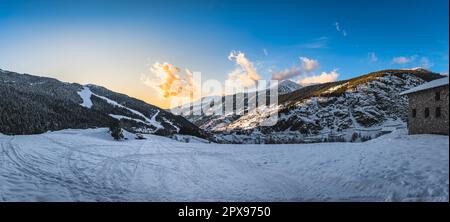 Vista panoramica sul villaggio di El Tarter con cielo, nuvole e montagne illuminate dal tramonto. Sci vacanze invernali ad Andorra, Pirenei Foto Stock