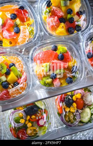 Scatole di plastica con macedonie di frutta preconfezionate, messe in vendita in un frigorifero commerciale Foto Stock