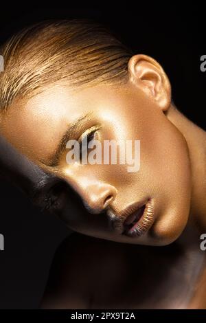 Ragazza beautyful con glitter d'oro sul suo viso.Arte immagine bellezza viso. Foto scattata in studio su sfondo nero. Foto Stock