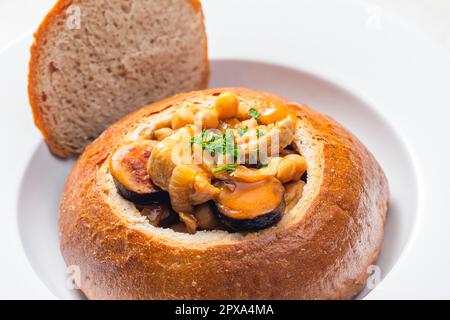 stufato con carne di maiale, ceci e sausge in pane Foto Stock