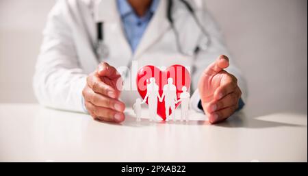 Medico di protezione mano cuore rosso con la famiglia figura sulla scrivania riflettente Foto Stock