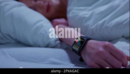 Smartwatch indossabile con monitoraggio della frequenza cardiaca in modalità sleep tracking a letto Foto Stock