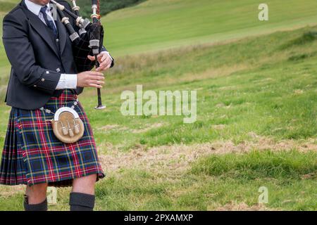 Bagpiper scozzese vestito in kilt tradizionale nelle Highlands della Scozia (con spazio per le copie) Foto Stock