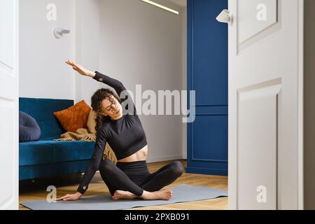 Giovane donna che lavora a casa e che fa stretching seduto sul pavimento Foto Stock