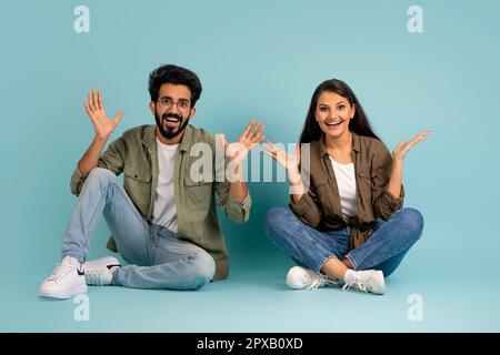 Sorpresa coppia multirazziale seduta sul pavimento e gesturing Foto Stock