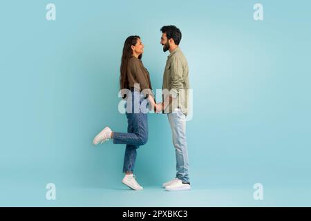 Bella coppia multiculturale giovane legame su blu, tenendo le mani Foto Stock