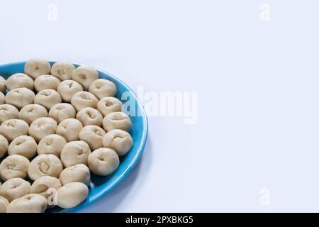 Mostrando mezza piastra di una piccola polpa di pasta cruda di pane appena fermentata fatta in casa sul lato sinistro di una tavola bianca Foto Stock