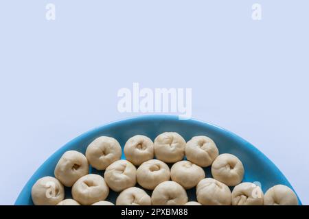 Mostrando mezza piastra di una piccola pasta cruda di pane appena fermentata fatta in casa su un tavolo bianco Foto Stock