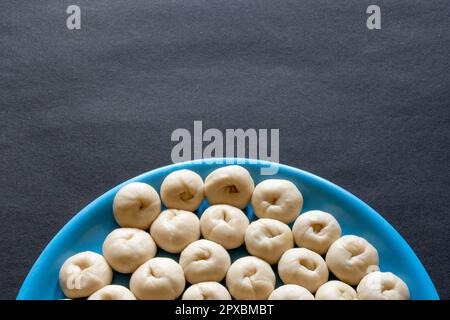 Mostrando mezza piastra di una piccola pasta cruda di pane appena fermentata fatta in casa su un tavolo nero Foto Stock