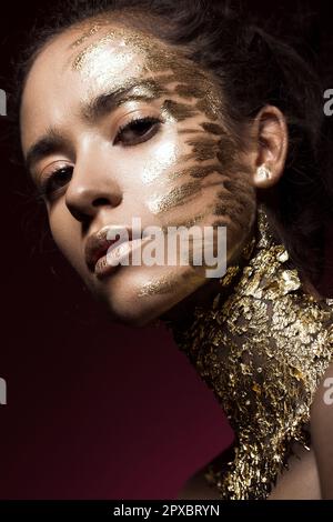 Ragazza beautyful con glitter d'oro sul suo viso.Arte immagine bellezza viso. Foto scattata in studio. Foto Stock