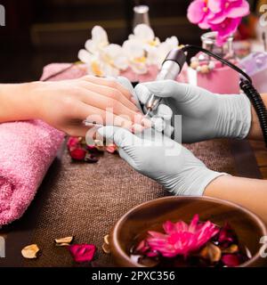 Cura delle unghie del dito del primo piano da specialista di manicure in salone di bellezza. Utensile elettrico professionale per manicure e pedicure. Foto Stock