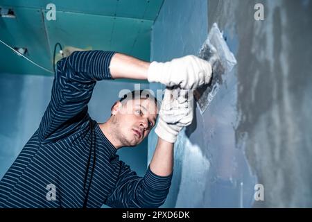 applicazione manuale di impermeabilizzazione alla parete in cantiere. Foto Stock