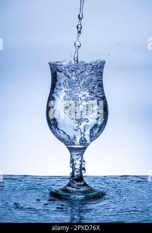 L'immagine di versare acqua potabile, in un vetro rotto, che fa sentire rinfrescato su sfondo bianco sfocato, spruzzi d'acqua, acqua frizzante, Foto Stock