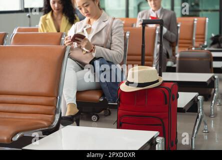 Passeggeri d'affari in attesa di volo nel terminal dell'aeroporto. Uomo e donna in tuta con passaporto e controllo del volo. Messa a fuoco selettiva su r Foto Stock