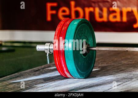 primo piano con piatti rossi e verdi su piattaforma in legno durante la gara di powerlifting Foto Stock