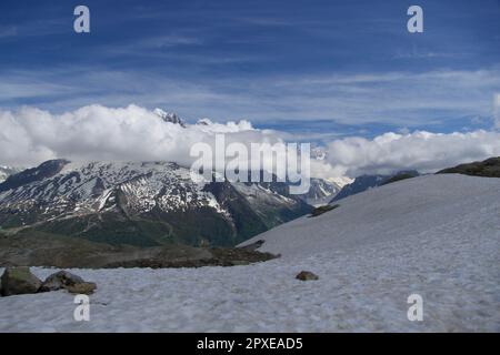 Uno splendido paesaggio caratterizzato da una montagna innevata del Monte Bianco sotto un cielo blu con nuvole. Foto Stock