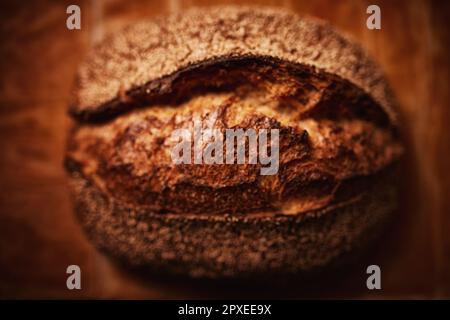 Una pagnotta di pane artigianale appena sfornata con una leggera spolveratura di farina sulla crosta dorata Foto Stock