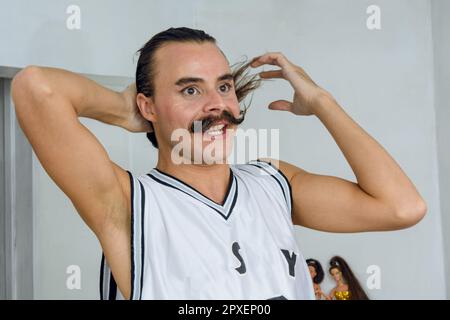 Latina giovane di etnia argentina e di genere non binario indignato nella sua stanza legando i capelli, in piedi parlando e lamentandosi. Foto Stock