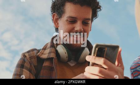 Primo piano di un giovane uomo che utilizza un telefono cellulare. Ritratto di un ragazzo felice che scrive un messaggio sui social media sul suo telefono cellulare Foto Stock