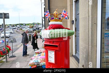 Rottingdean , Brighton UK 2nd Maggio 2023 - la casella postale rossa nel villaggio di Rottingdean vicino Brighton è decorata con una corona lavorata a maglia pronta per l'imminente incoronazione di Re Carlo III Sabato 6th Maggio : Credit Simon Dack / Alamy Live News Foto Stock