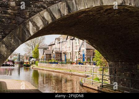 Vista attraverso il ponte verso i cottage sul canale a Monmouthshire e il bacino del canale Brecon a Brecon (Aberhonddu), Powys, Galles, Regno Unito, Gran Bretagna Foto Stock