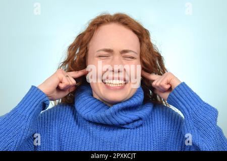 carina donna ricciola dai capelli rossi le coprì le orecchie con le dita e urla Foto Stock