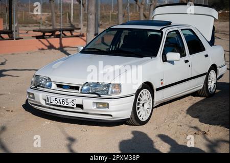 Particolare di una bella Ford Sierra Cosworth bianca. Il proprietario sta prendendo le cose dal bagagliaio Foto Stock