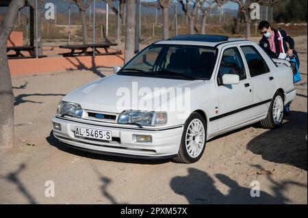 Particolare di una bella Ford Sierra Cosworth bianca. Il proprietario sta prendendo le cose dal bagagliaio Foto Stock