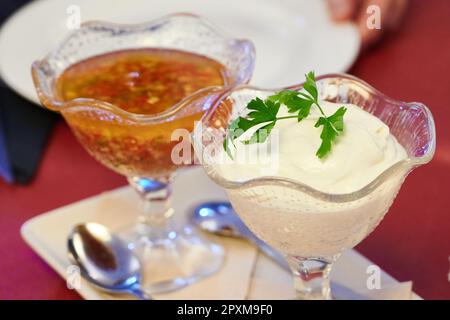 Salse di vinaigrette sullo sfondo e maionese in primo piano con alcune foglie di prezzemolo per la decorazione Foto Stock